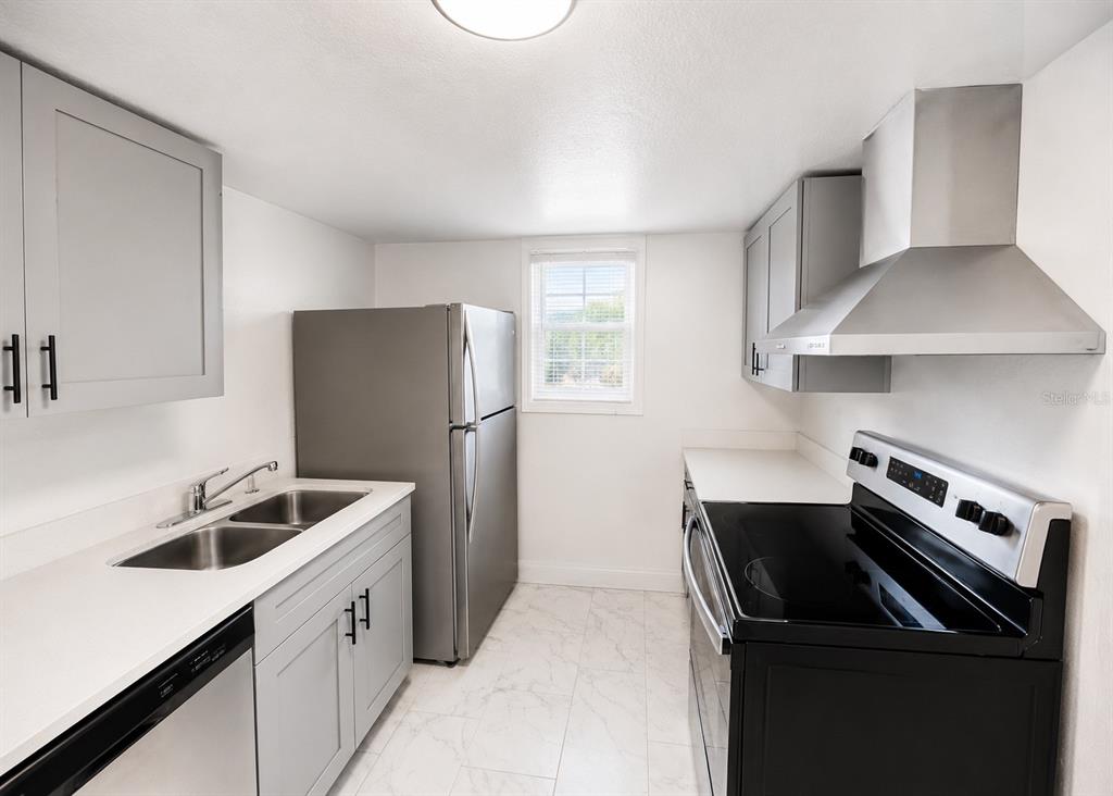 A galley kitchen features gray cabinets, stainless steel appliances, white countertops, and light tile flooring — 2751 L B MCLEOD ROAD UNIT C, ORLANDO, FL