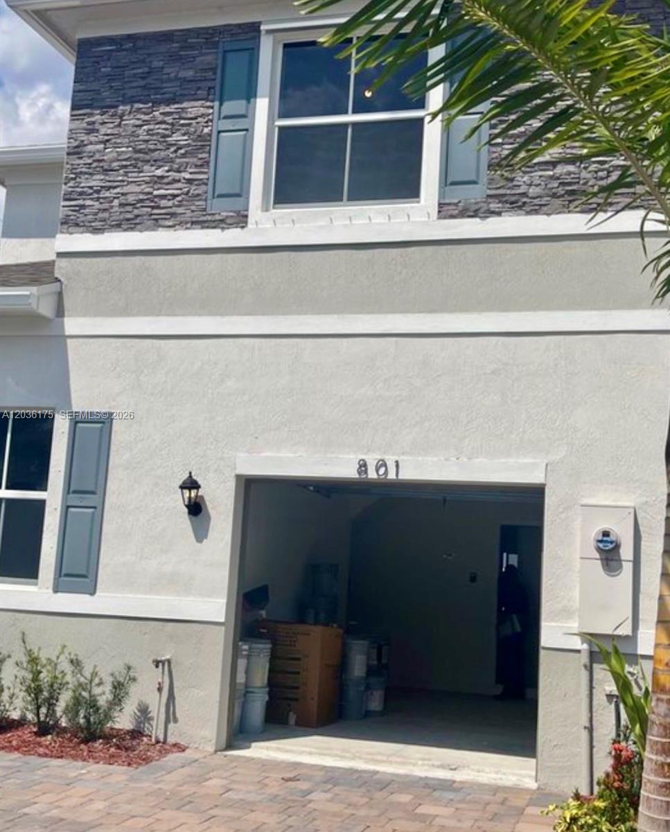 The exterior of a two-story home features a garage, stone veneer, and blue shutters — HOMESTEAD, FL