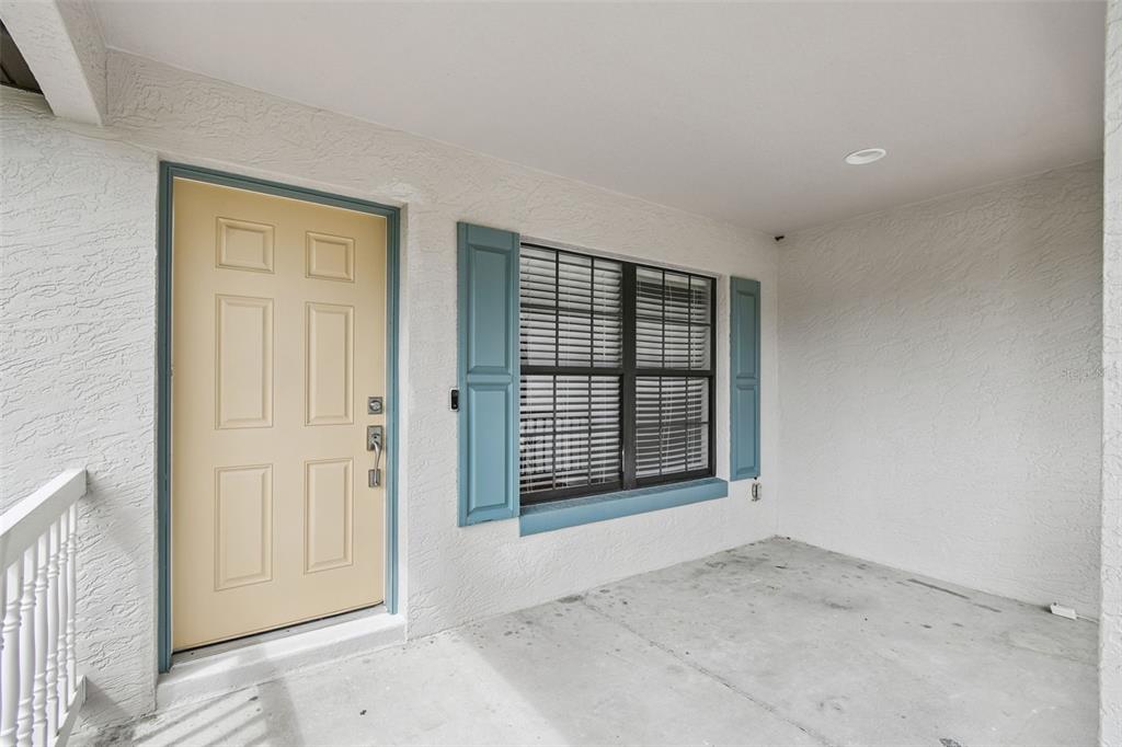 A covered porch features a light yellow front door and a window with blue shutters — 209 GOLDIE STREET, LEESBURG, FL