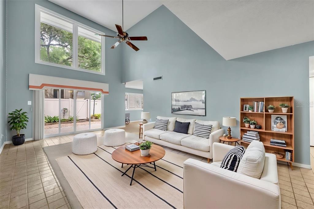 A living room with vaulted ceilings, light blue walls, tile flooring, and a large window — 497 OAK HAVEN DRIVE UNIT 497, ALTAMONTE SPRINGS, FL