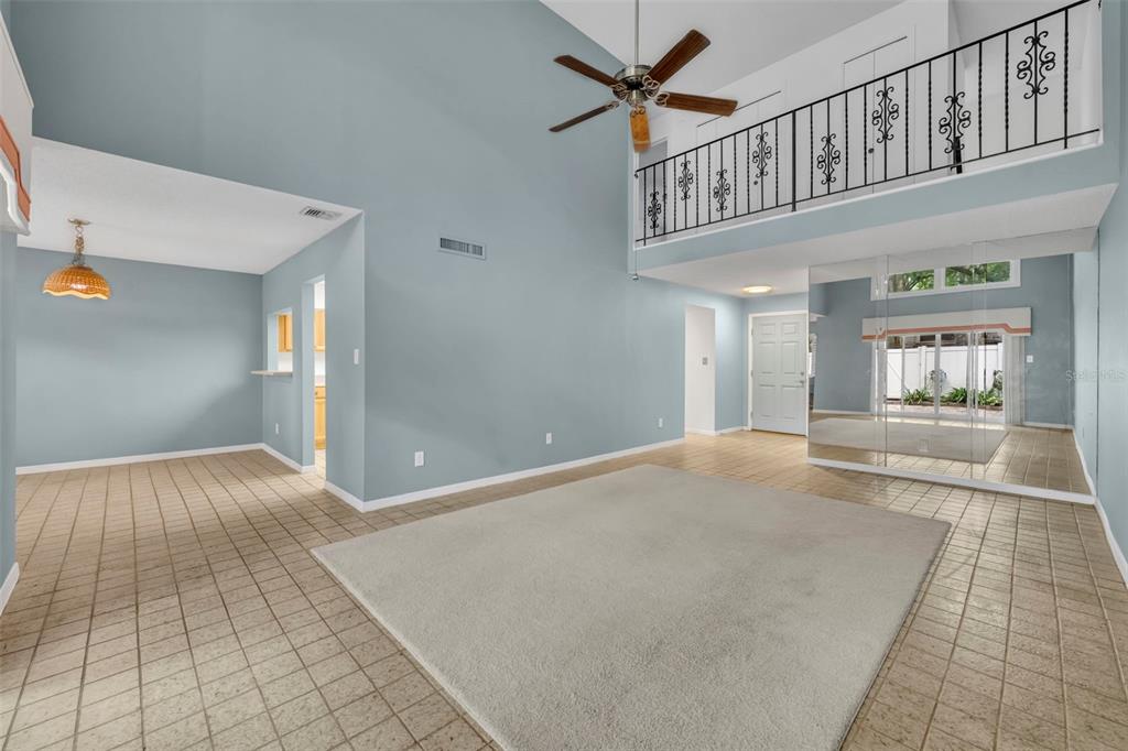 A living room with high ceilings, a carpeted area, tiled floors, and a balcony railing — 497 OAK HAVEN DRIVE UNIT 497, ALTAMONTE SPRINGS, FL