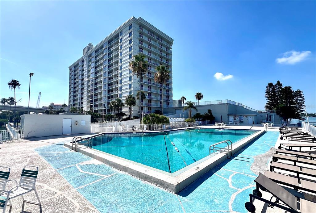 A swimming pool sits on a patio in front of a tall residential building — 100 PIERCE STREET UNIT 1001, CLEARWATER, FL