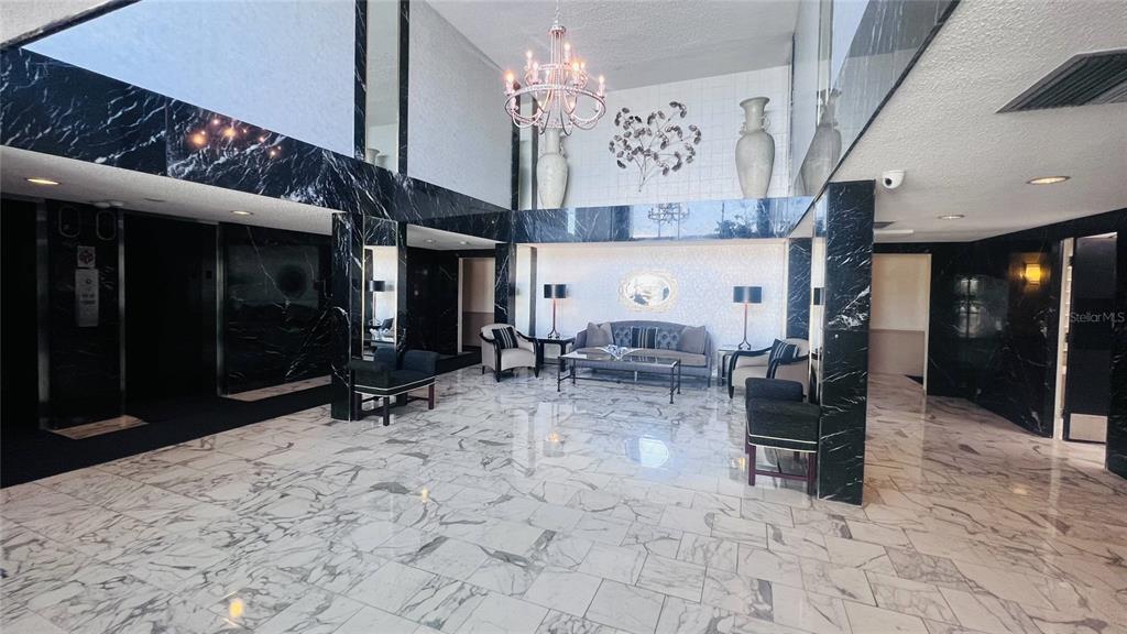 A spacious lobby features black marble accents, white marble flooring, and a central seating area — 100 PIERCE STREET UNIT 1001, CLEARWATER, FL