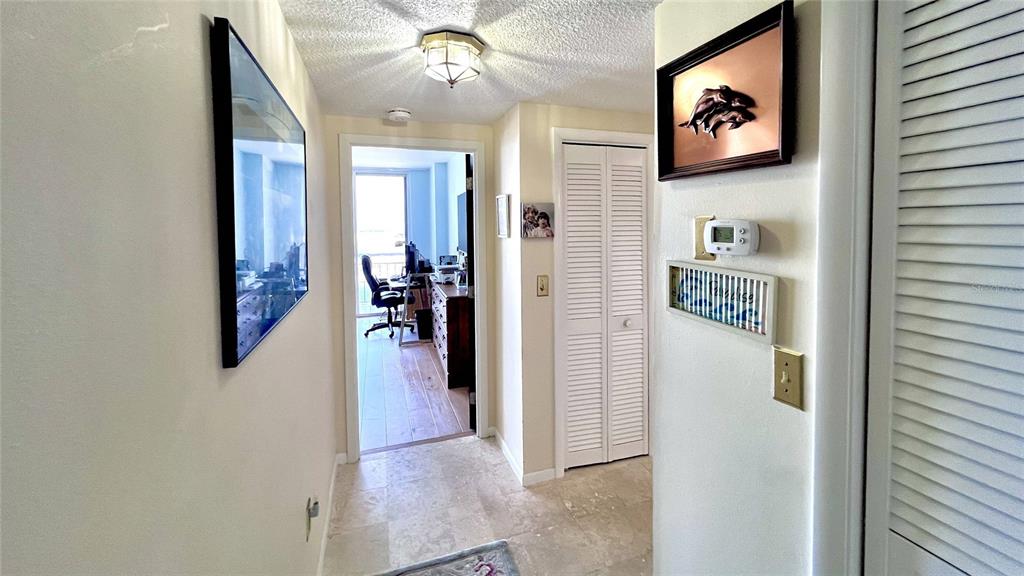 A hallway with tile flooring leads to a room with a desk and balcony view — 100 PIERCE STREET UNIT 1001, CLEARWATER, FL