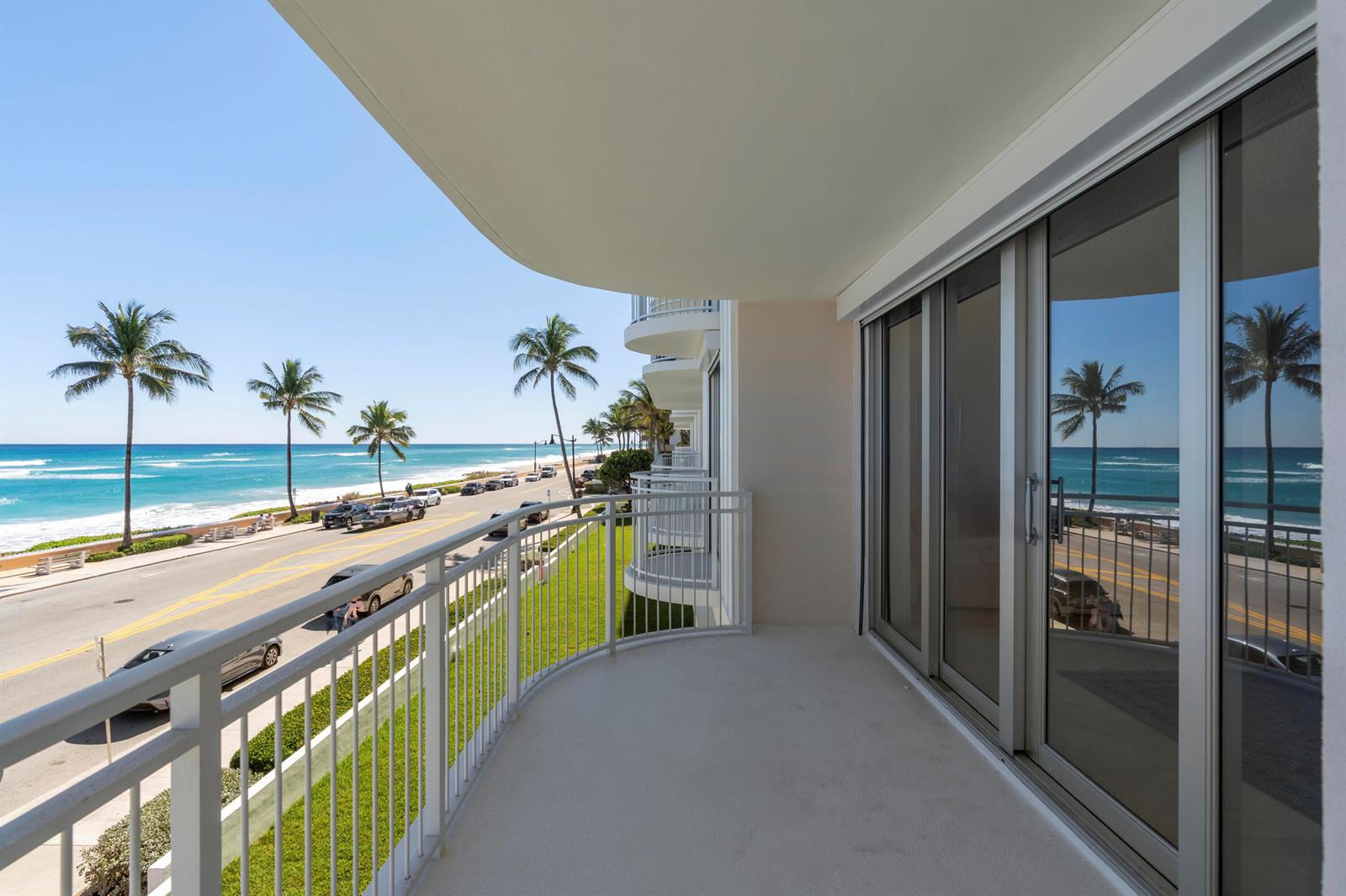 A balcony with a white metal railing overlooks a coastal road, beach, and ocean — 100 Worth Avenue # 310, Palm Beach FL 33480, PALM BEACH, FL