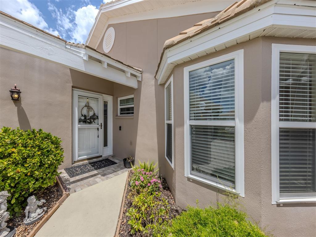A tan house exterior features a white front door, a walkway, and large windows — 525 CLUBSIDE CIRCLE UNIT 53, VENICE, FL