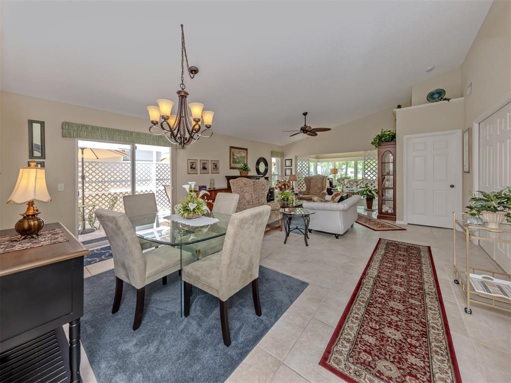 A dining area with a glass table and chairs opens into a living room space — 525 CLUBSIDE CIRCLE UNIT 53, VENICE, FL