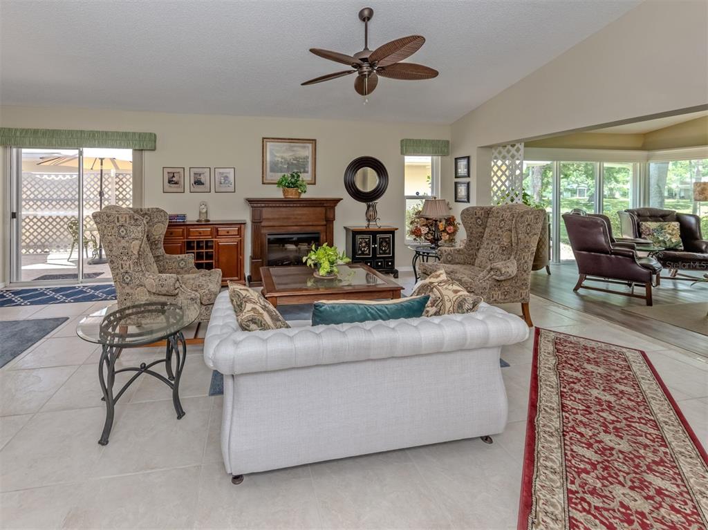 A living room features a fireplace, a tufted sofa, two patterned armchairs, and tile flooring — 525 CLUBSIDE CIRCLE UNIT 53, VENICE, FL