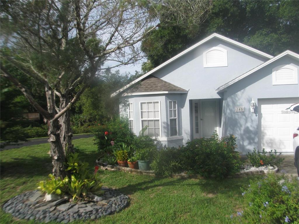 A light blue house with a bay window, a garage, and landscaped front yard — 145 CROOKED PINE ROAD, PORT ORANGE, FL
