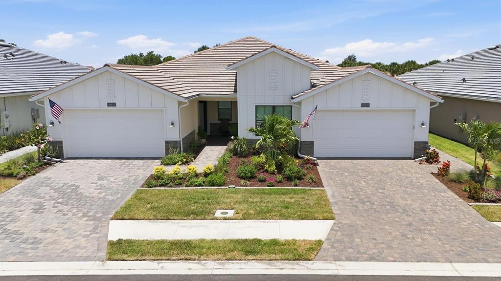 A single-story house with two garage doors, a paved driveway, and a central entryway — 18839 DAYSPRING PLACE, VENICE, FL