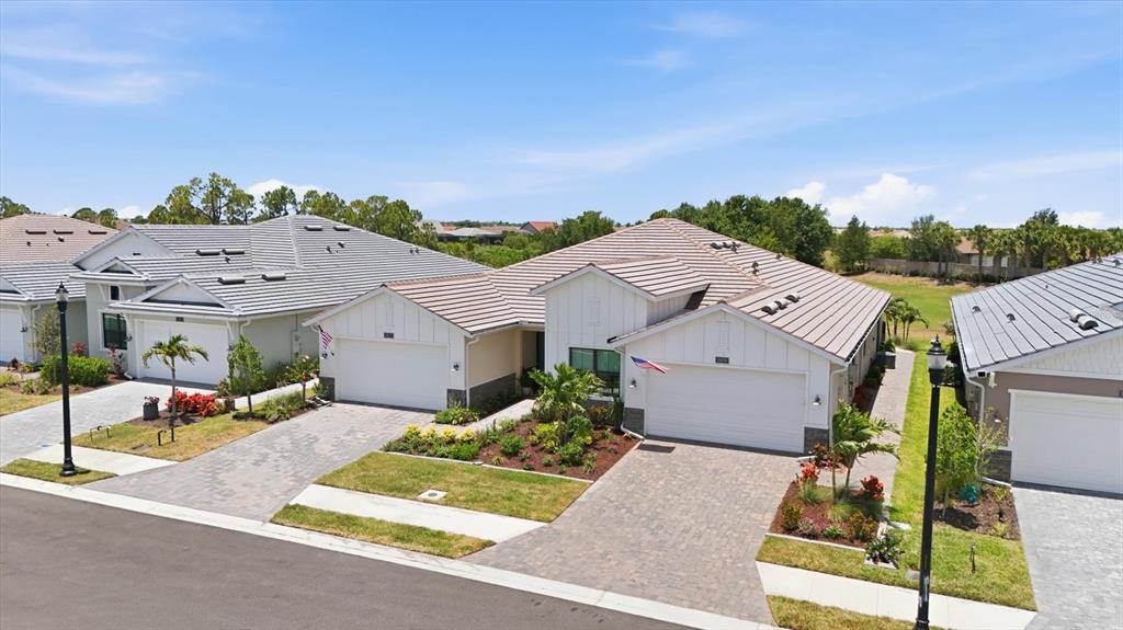 An aerial view shows three suburban houses with tiled roofs and paved driveways — 18839 DAYSPRING PLACE, VENICE, FL