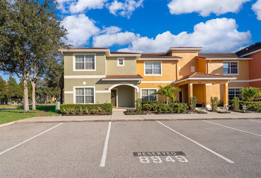 A two-story townhouse with a reserved parking space in the foreground — 8949 CANDY PALM ROAD, KISSIMMEE, FL