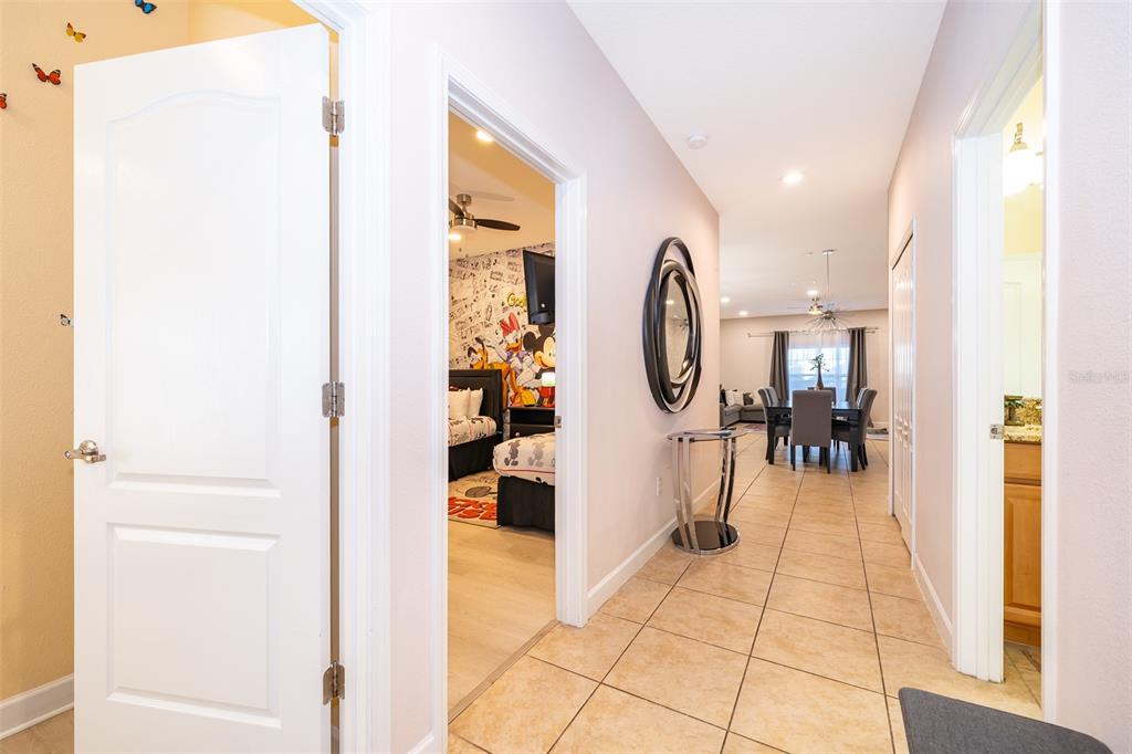 A hallway with tile flooring leads to a dining area past a bedroom and bathroom — 8949 CANDY PALM ROAD, KISSIMMEE, FL