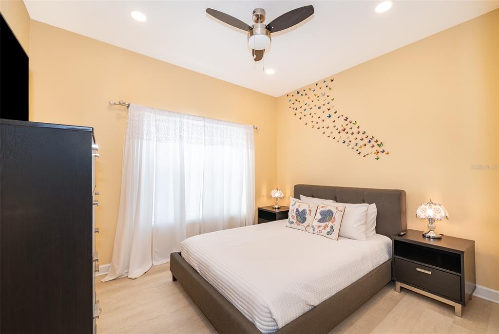 A bedroom features a bed with a gray headboard, butterfly wall decals, and a ceiling fan — 8949 CANDY PALM ROAD, KISSIMMEE, FL