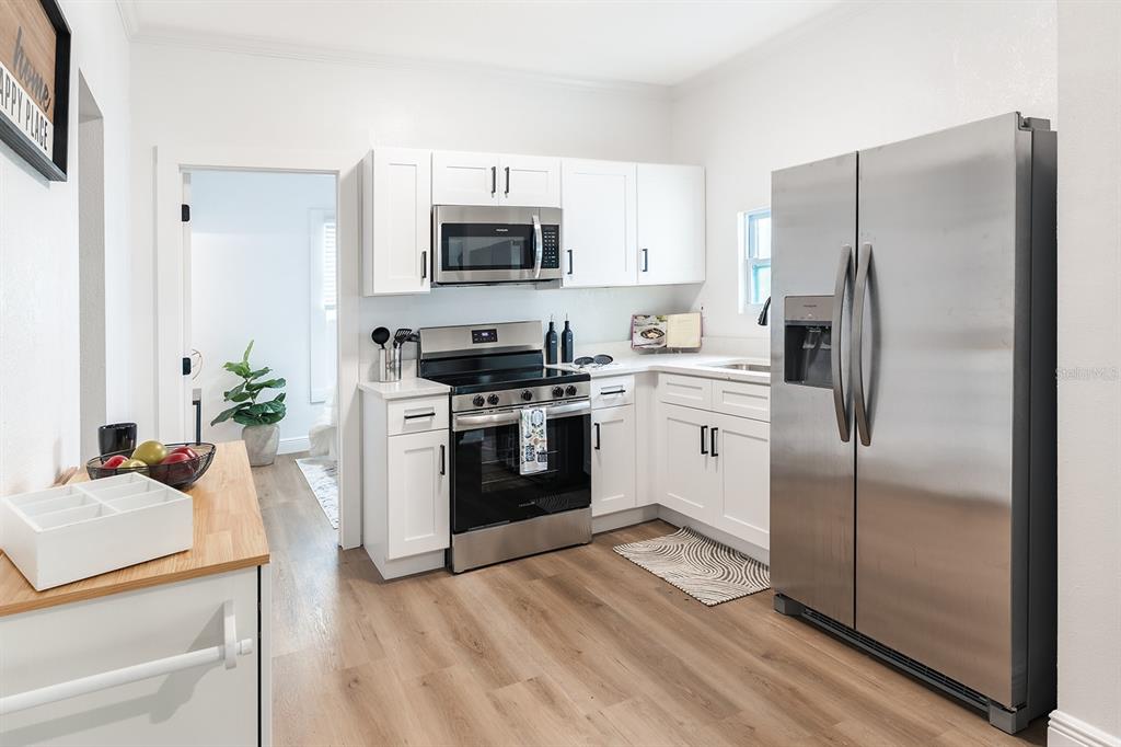 A kitchen features white cabinets, stainless steel appliances, and light wood-look flooring — 4324 EMERSON AVENUE S, ST PETERSBURG, FL