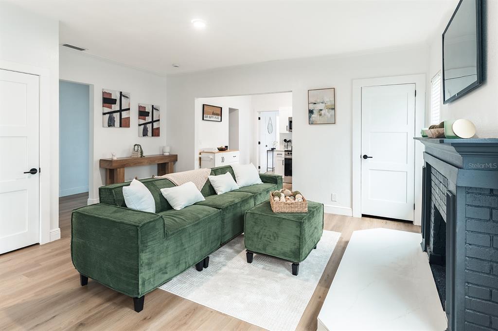 A living room features a green corduroy sofa, a matching ottoman, and a dark fireplace — 4324 EMERSON AVENUE S, ST PETERSBURG, FL