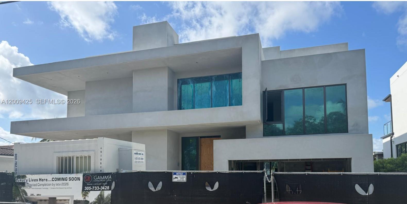 A modern, multi-story concrete house under construction with large glass windows and a fenced perimeter — 2060 S Hibiscus Dr, North Miami FL 33181, NORTH MIAMI, FL