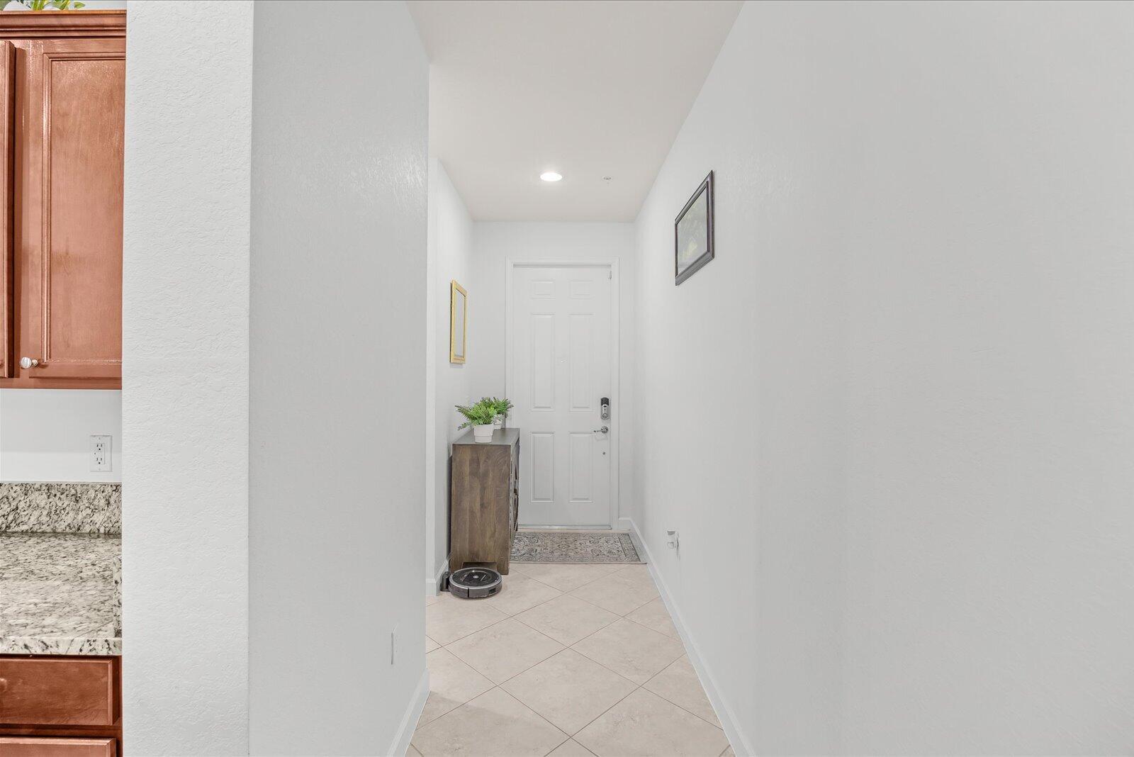 A narrow entryway features tile flooring, a white door, and a wooden console table — 9500 SW Otter Lane, Stuart FL 34997, STUART, FL