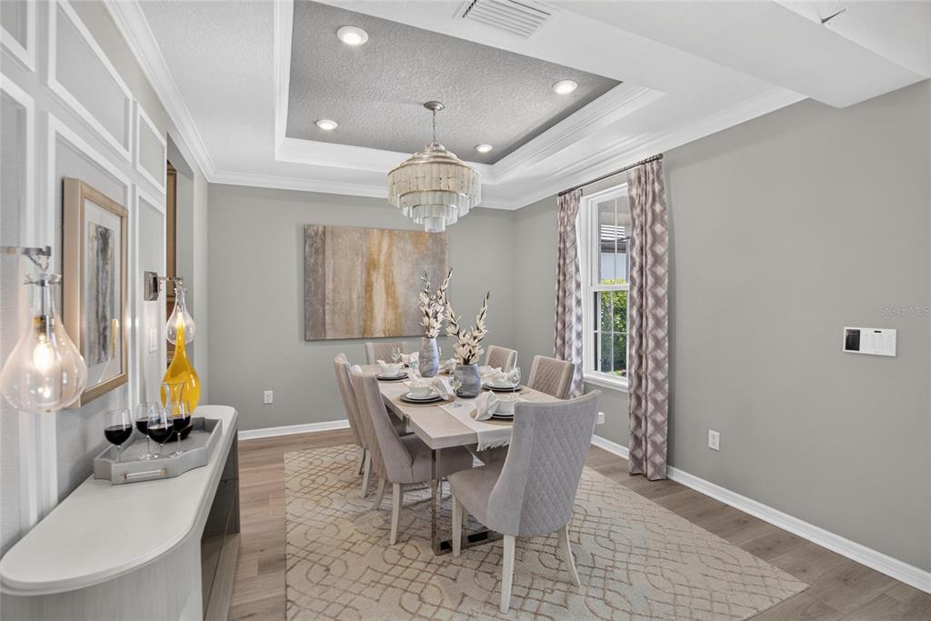 A dining room features a tray ceiling, a crystal chandelier, and a rectangular table — 8228 SUMMER NIGHT ROAD, SARASOTA, FL