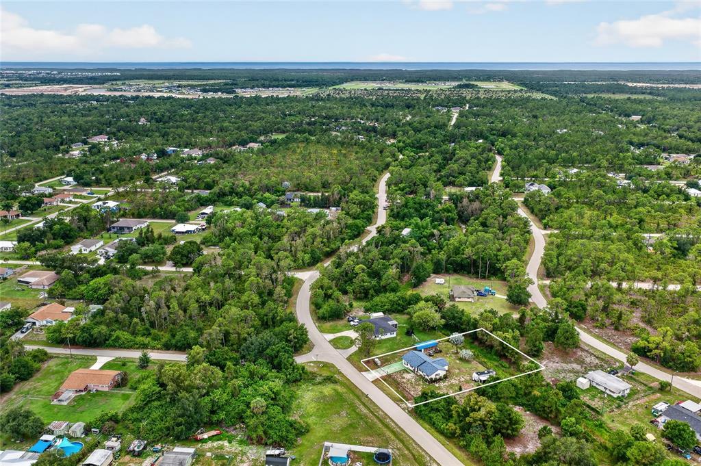An aerial view shows a single-story house with a white outline on a wooded lot — 27484 S TWIN LAKES DRIVE, PUNTA GORDA, FL