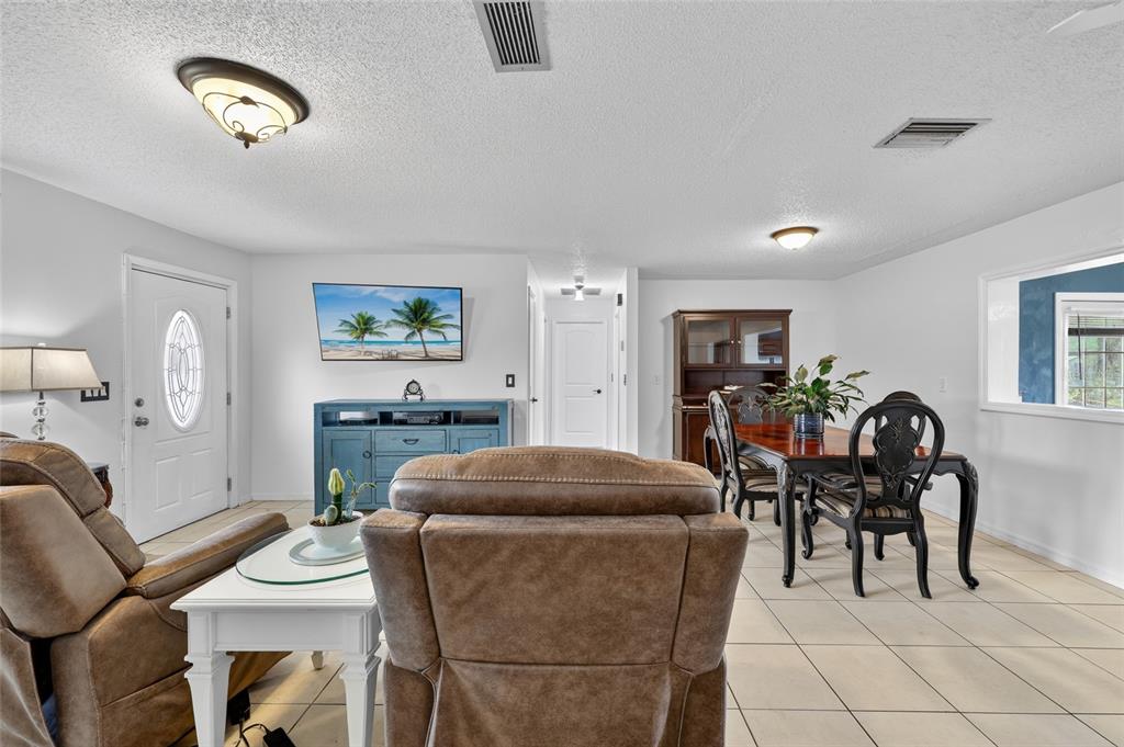 A living and dining area with tile floors, a brown recliner, and a blue media console — 27484 S TWIN LAKES DRIVE, PUNTA GORDA, FL