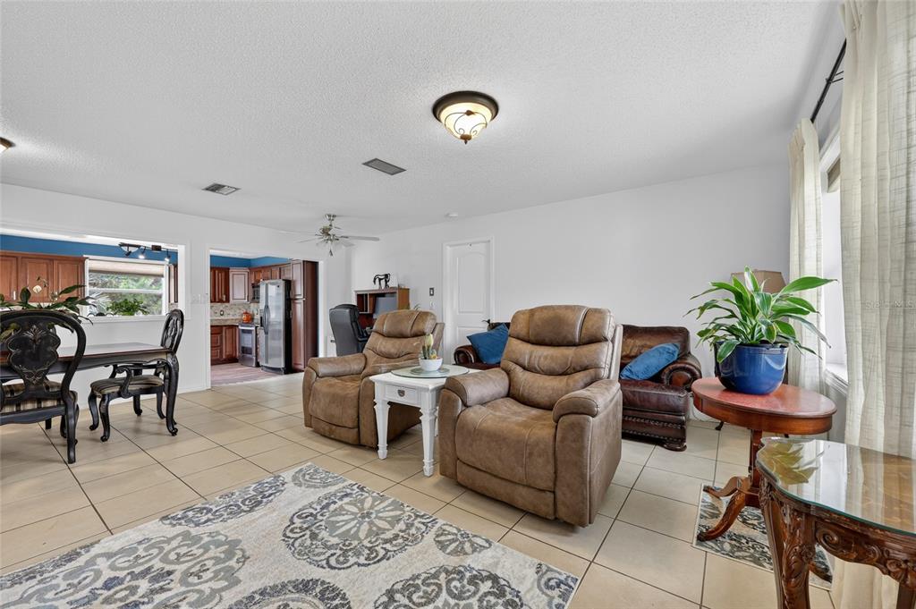 A living room with tile floors, two brown recliners, and an adjacent dining area — 27484 S TWIN LAKES DRIVE, PUNTA GORDA, FL
