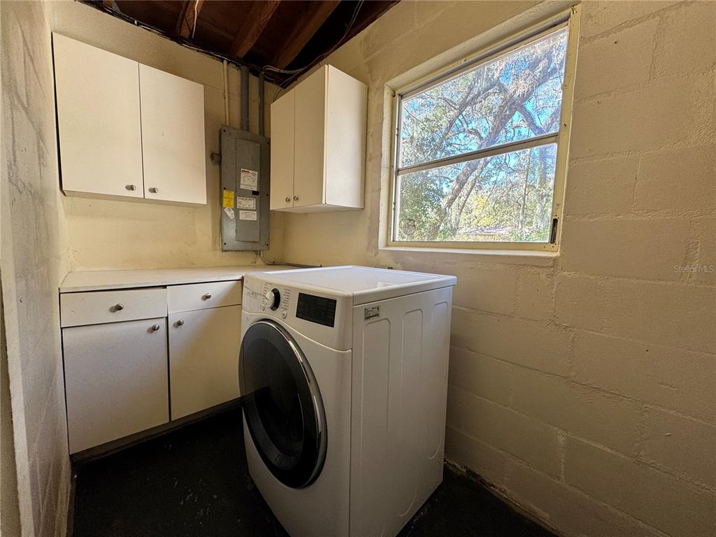 A laundry room features white cabinets, a front-loading washer, and a window on block walls — 310 LONGWOOD DRIVE, BROOKSVILLE, FL