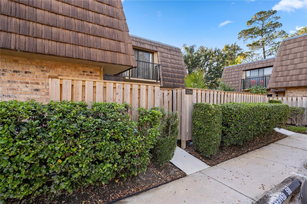 A wooden fence encloses a patio area in front of a multi-story townhouse complex — 5284 WILLOW COURT UNIT 508, ORLANDO, FL