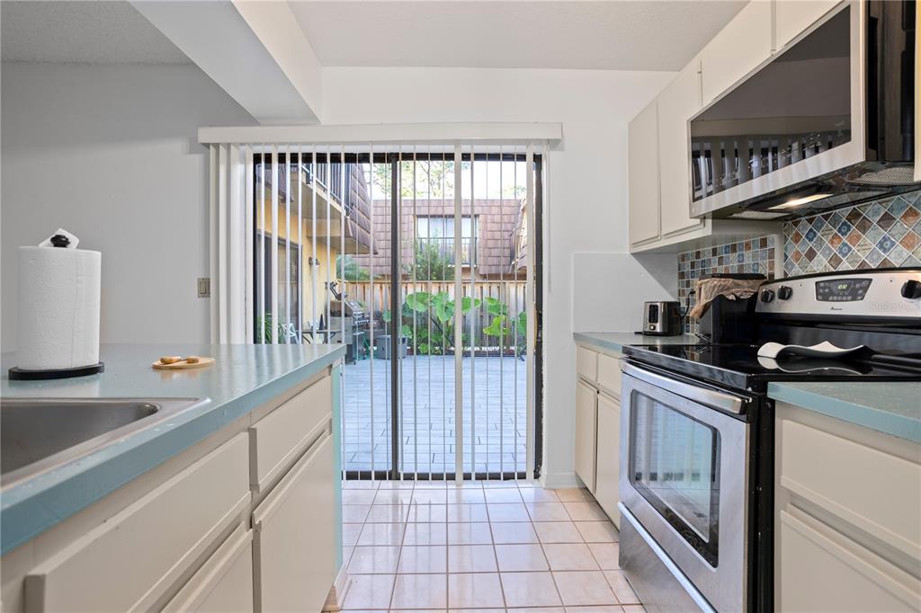 A kitchen with light cabinets, blue countertops, and a sliding glass door to a patio — 5284 WILLOW COURT UNIT 508, ORLANDO, FL