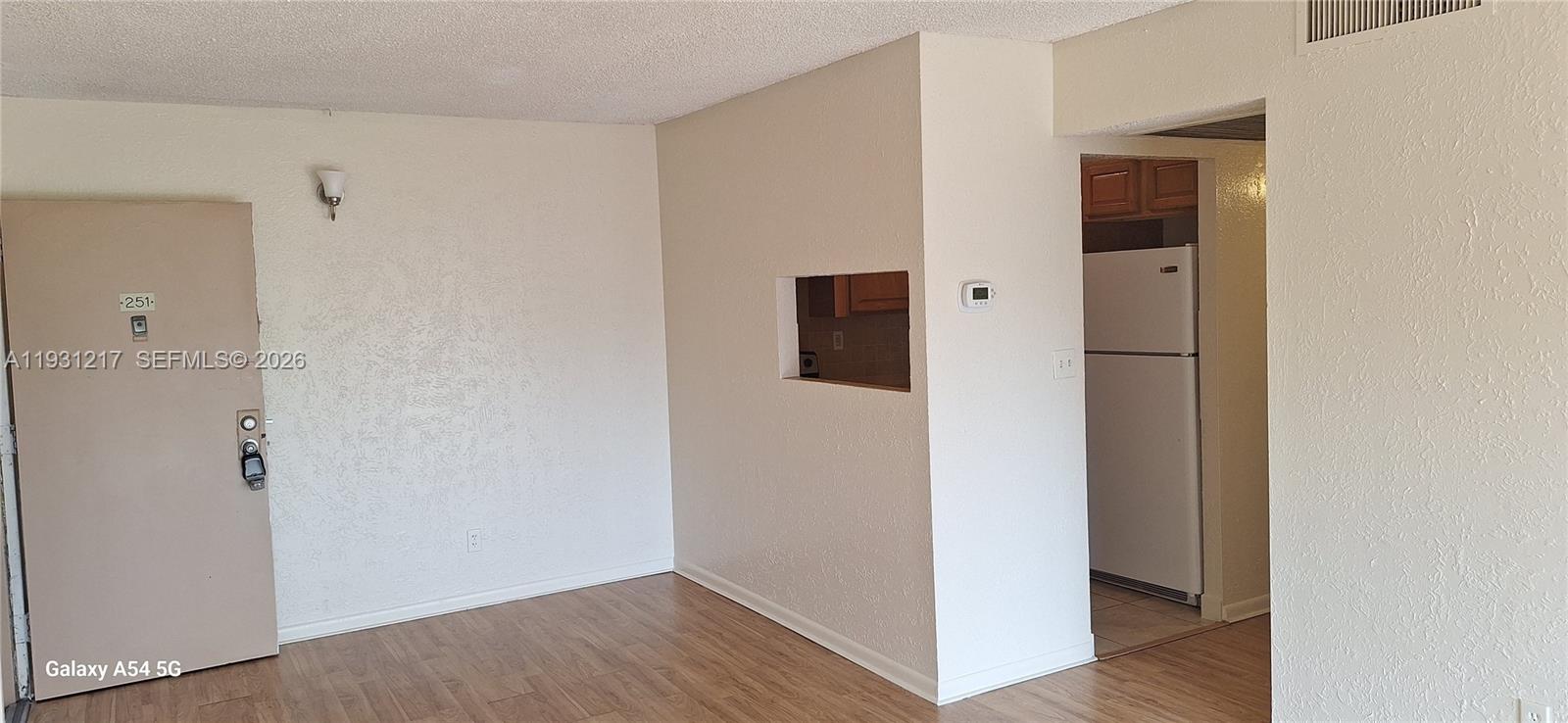 This interior view shows a living area with wood-look flooring and a kitchen pass-through window — 5901 Washington St # 251, Hollywood FL 33023, HOLLYWOOD, FL