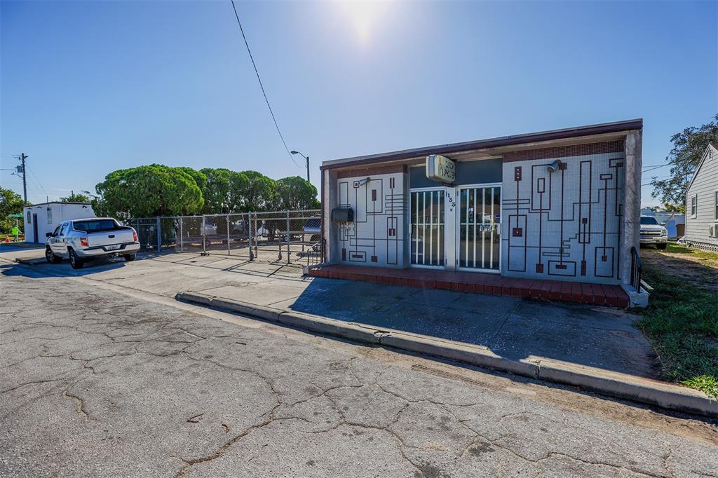 A single-story commercial building with a geometric mural on its facade and a gated lot — 133 W STUART AVENUE, LAKE WALES, FL