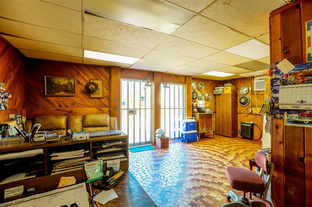A room with wood-paneled walls, a tiled floor, a drop ceiling, and a desk area — 133 W STUART AVENUE, LAKE WALES, FL