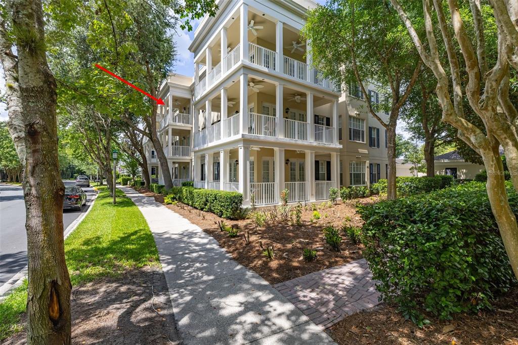 A three-story apartment building with white balconies and a sidewalk in the foreground — 855 BLUE SAGE STREET UNIT 302, CELEBRATION, FL