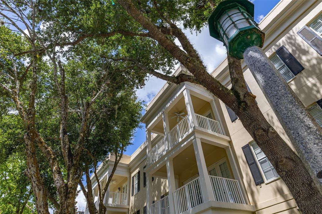A low-angle view of a multi-story building exterior with balconies and a prominent street lamp — 855 BLUE SAGE STREET UNIT 302, CELEBRATION, FL