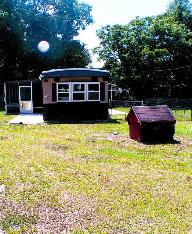 A mobile home with a dark exterior and a small shed sits on a grassy lot — 11838 SE 99TH COURT, BELLEVIEW, FL