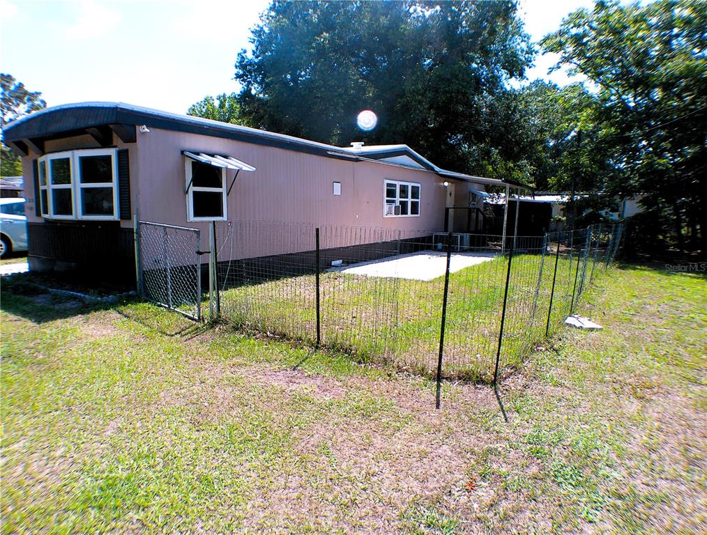 A single-story mobile home with a fenced yard and a small concrete patio — 11838 SE 99TH COURT, BELLEVIEW, FL