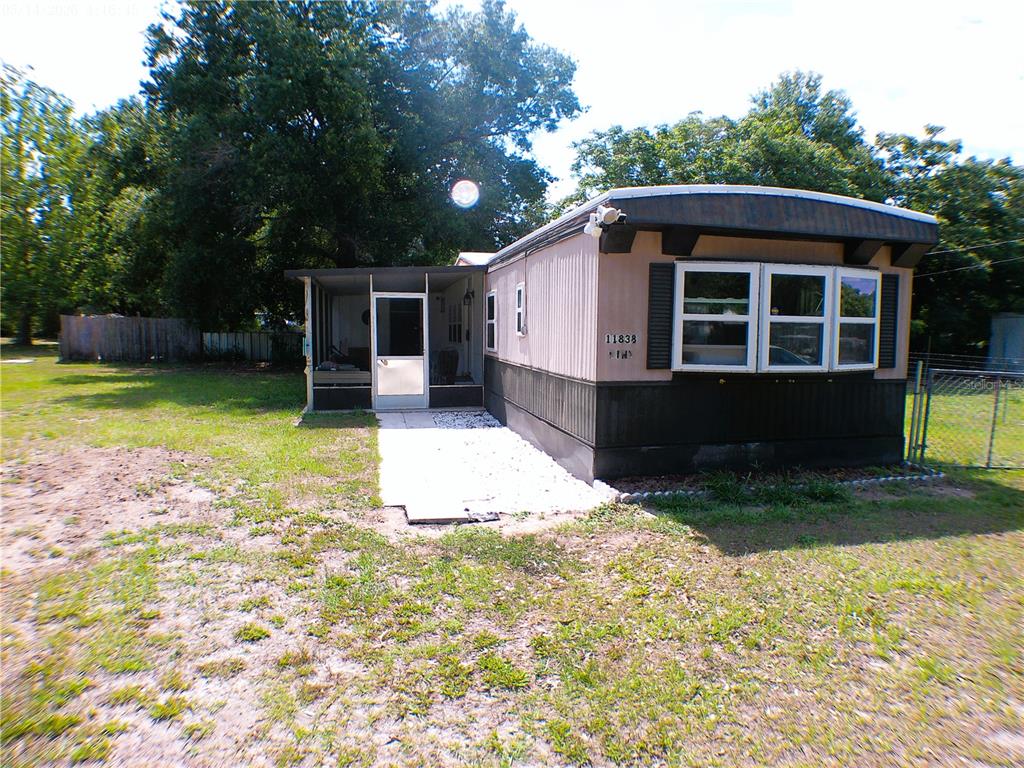 A single-story mobile home with a screened-in porch and a white gravel walkway — 11838 SE 99TH COURT, BELLEVIEW, FL