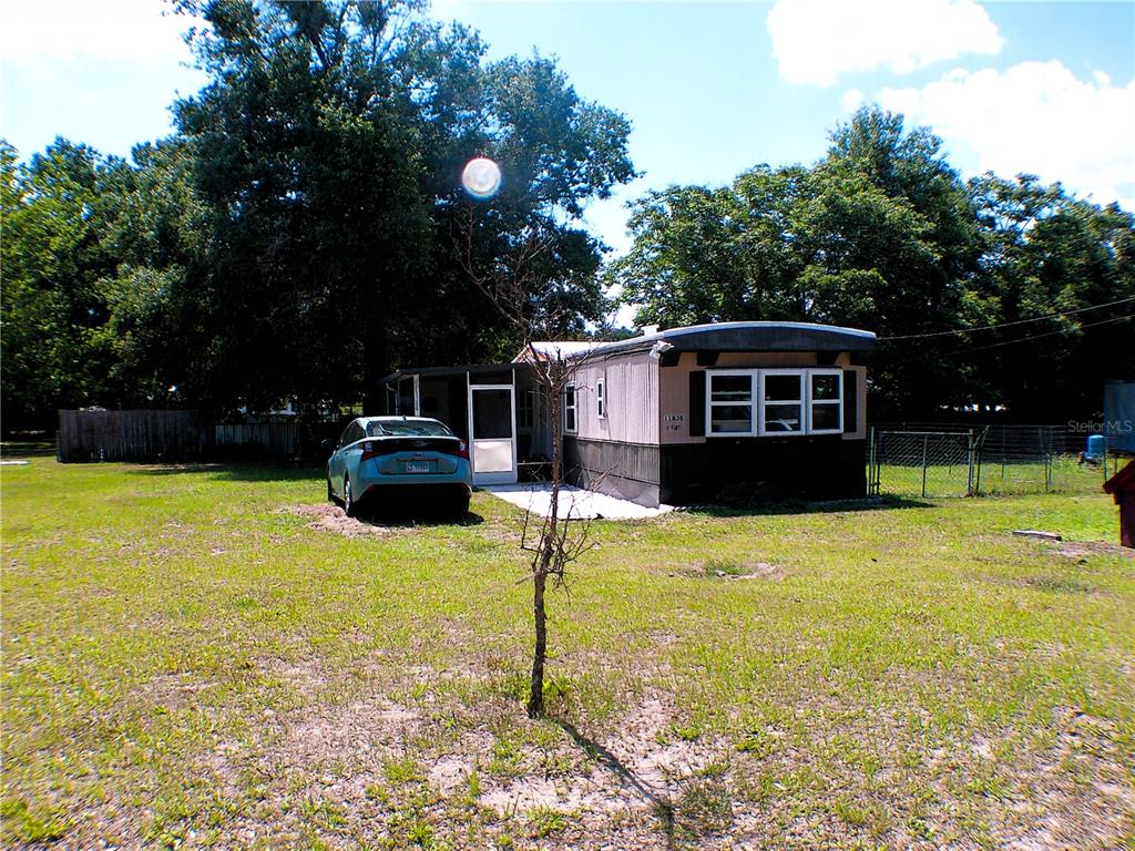 A single-story mobile home sits on a grassy lot with a car parked nearby — 11838 SE 99TH COURT, BELLEVIEW, FL