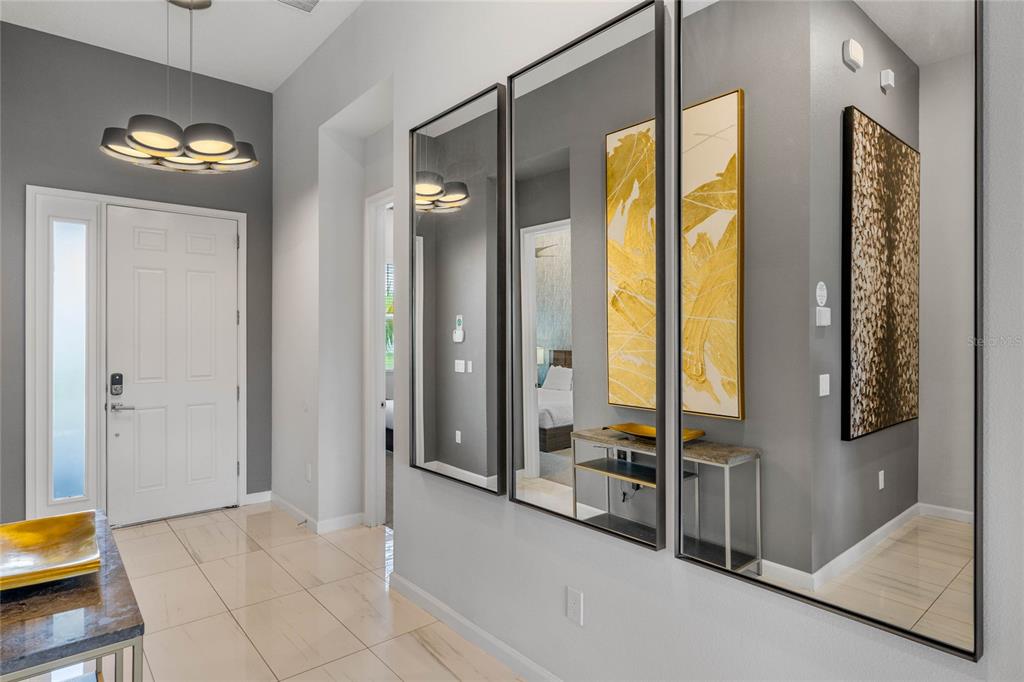 A bright entryway features tiled floors, a modern light fixture, and three large wall mirrors — 1743 OAK BLOSSOM DRIVE, DAVENPORT, FL