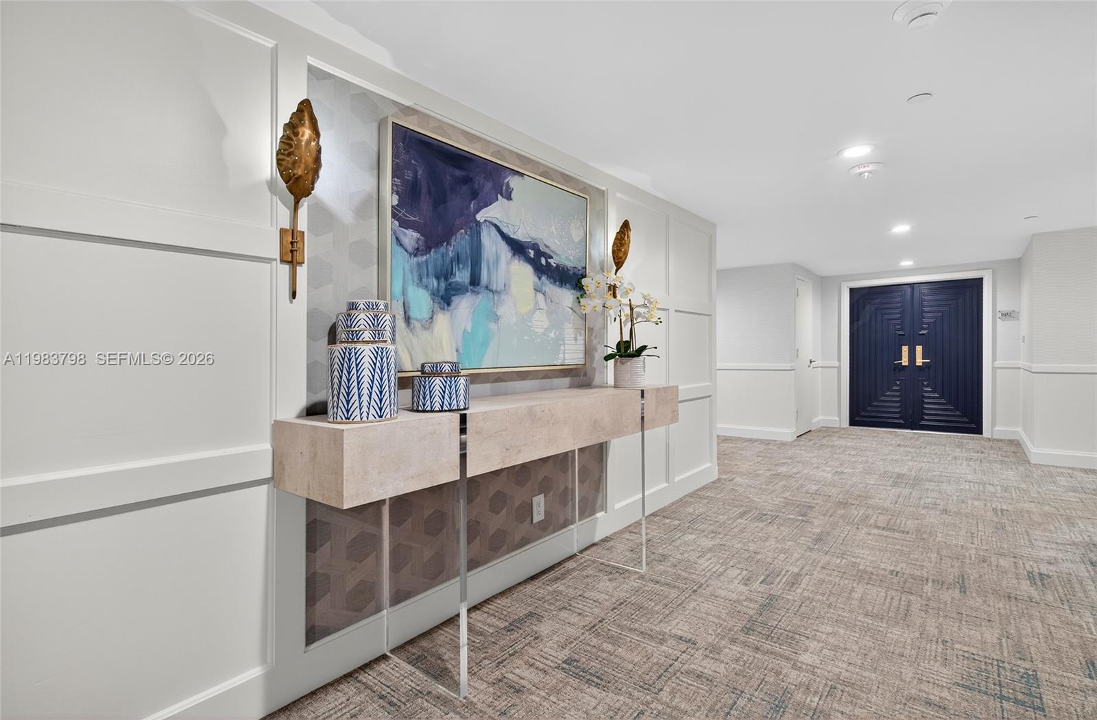 A hallway features a console table, abstract artwork, and a dark blue double door — 19670 Beach Rd # A601, Tequesta FL 33469, TEQUESTA, FL
