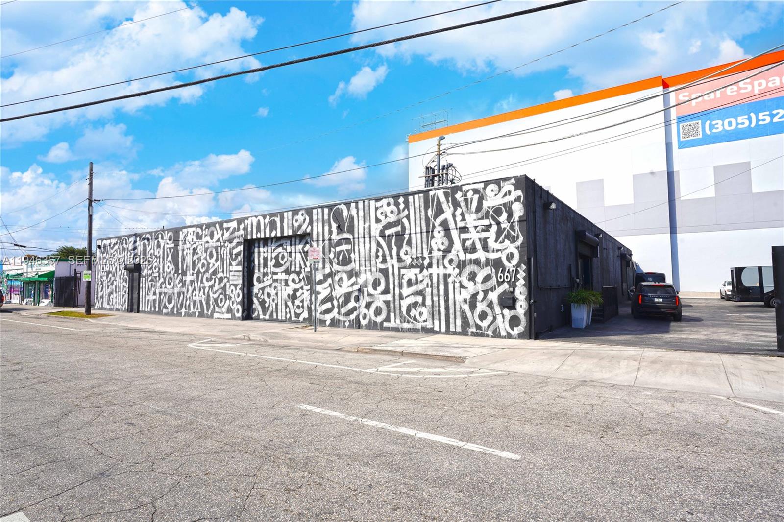 A black building exterior features white graffiti-style mural art and a side parking area — 667 NW 29th St, Miami FL 33127, MIAMI, FL