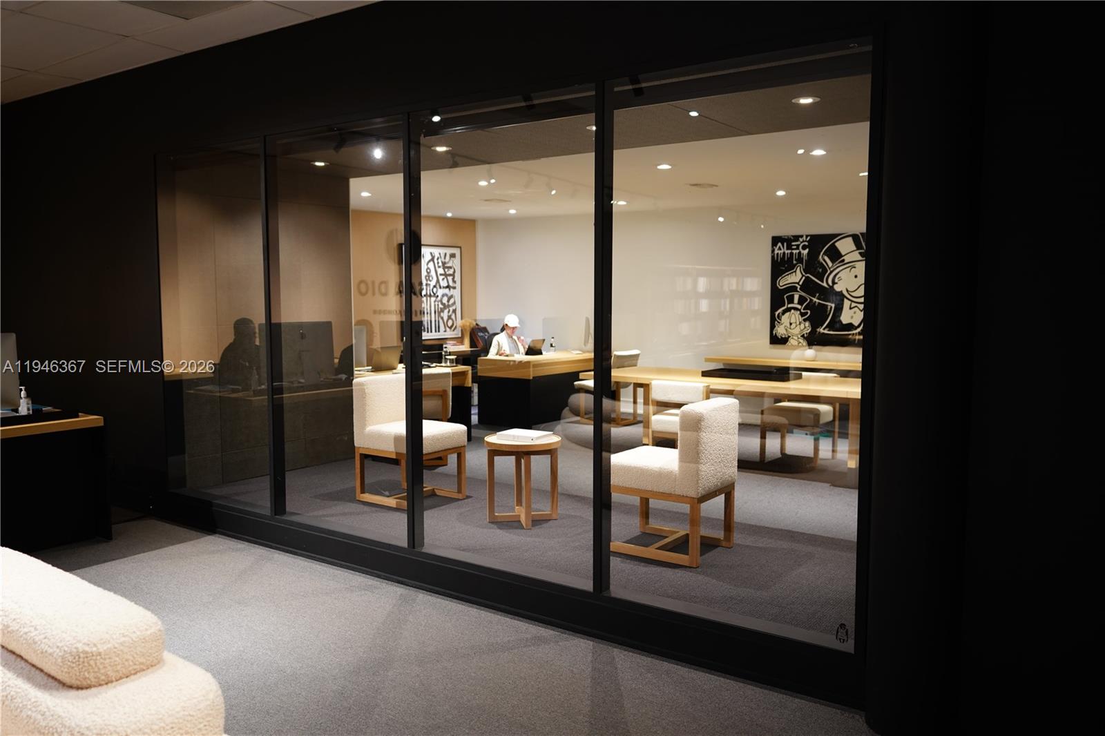 A glass-enclosed office space features two cream-colored chairs, a small table, and a desk — 667 NW 29th St, Miami FL 33127, MIAMI, FL