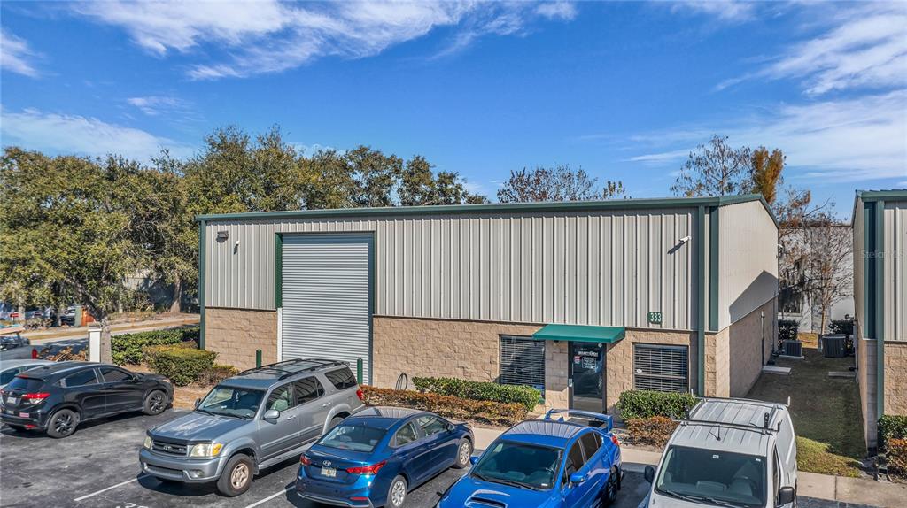 An exterior view of a single-story commercial building with a roll-up door and parking — 333 GORDON STREET, SANFORD, FL