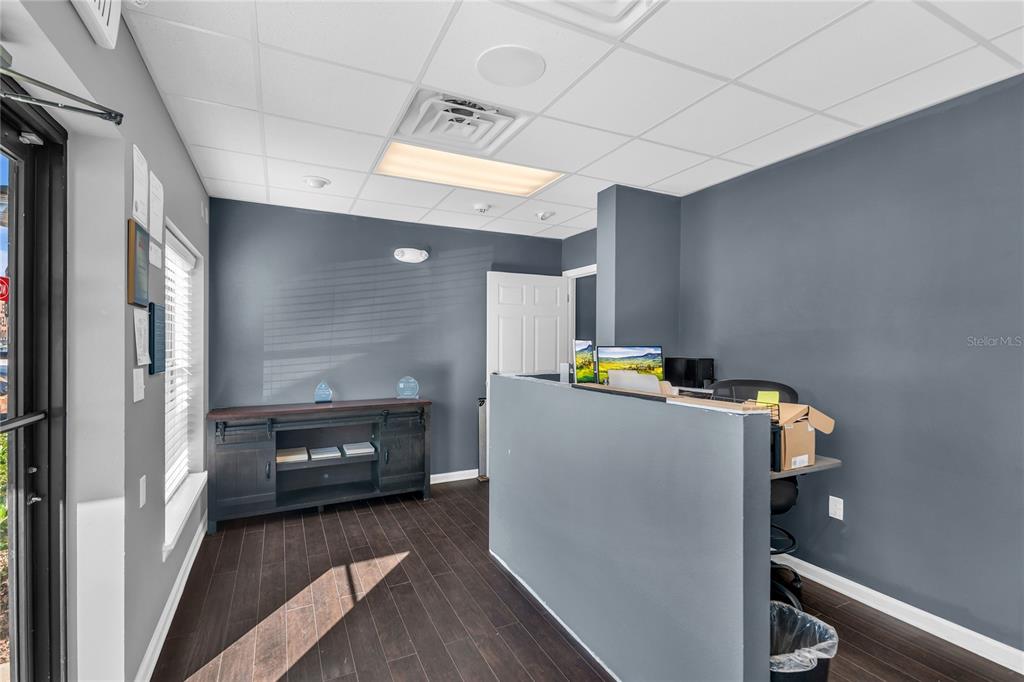 A reception area features a dark gray desk, wood-look flooring, and a dark wood console — 333 GORDON STREET, SANFORD, FL