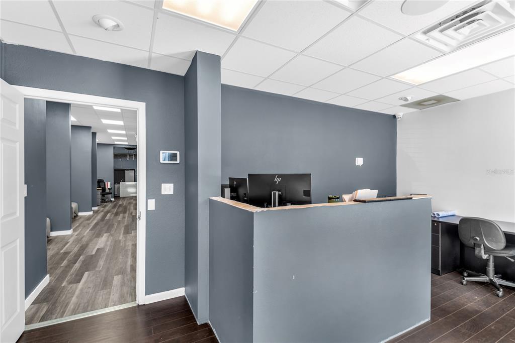 A reception area features a dark gray desk, wood-look flooring, and a doorway to a hallway — 333 GORDON STREET, SANFORD, FL