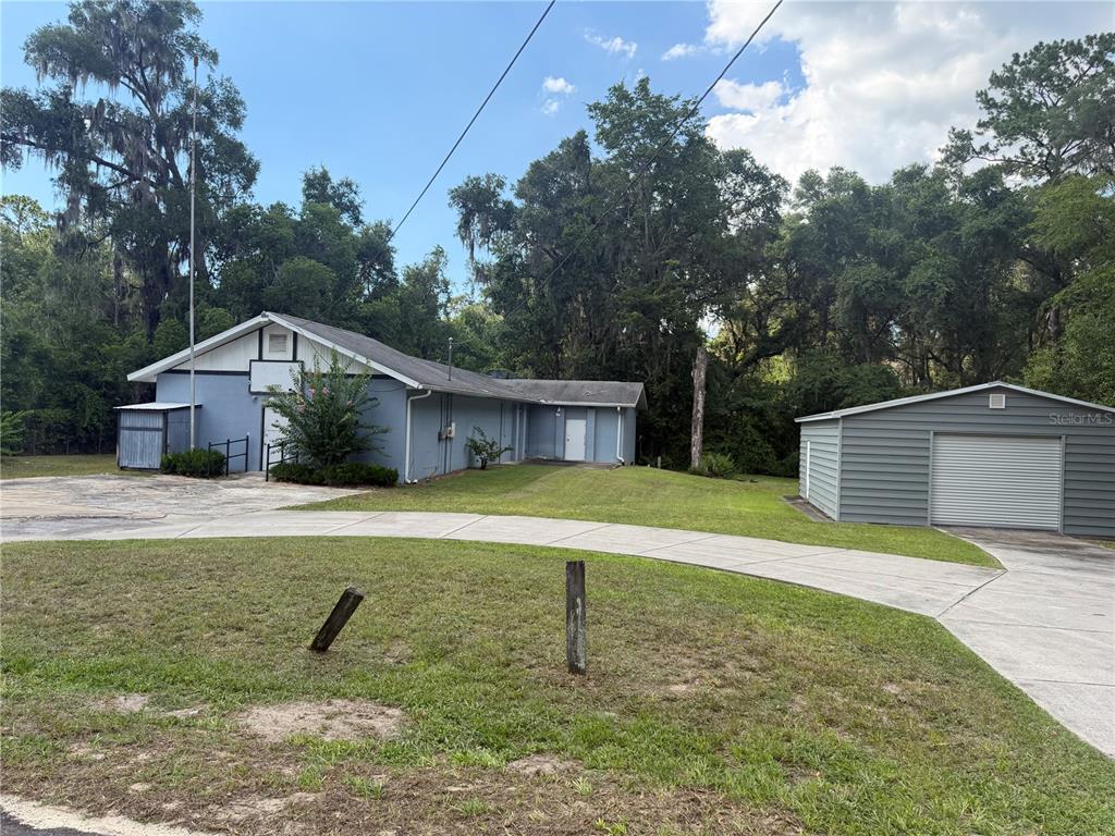 A blue building with a white trim and a detached garage sit on a grassy lot — 5561 NE 35TH STREET, SILVER SPRINGS, FL