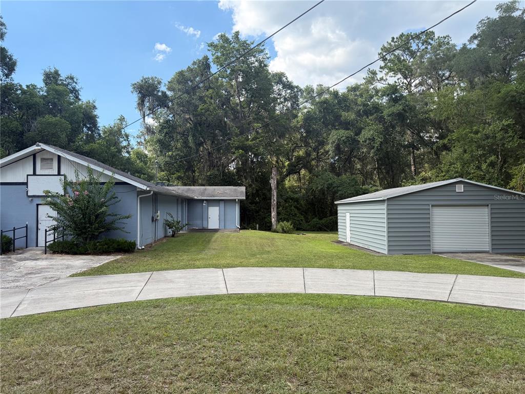 A blue house and a detached gray garage sit on a grassy lot — 5561 NE 35TH STREET, SILVER SPRINGS, FL