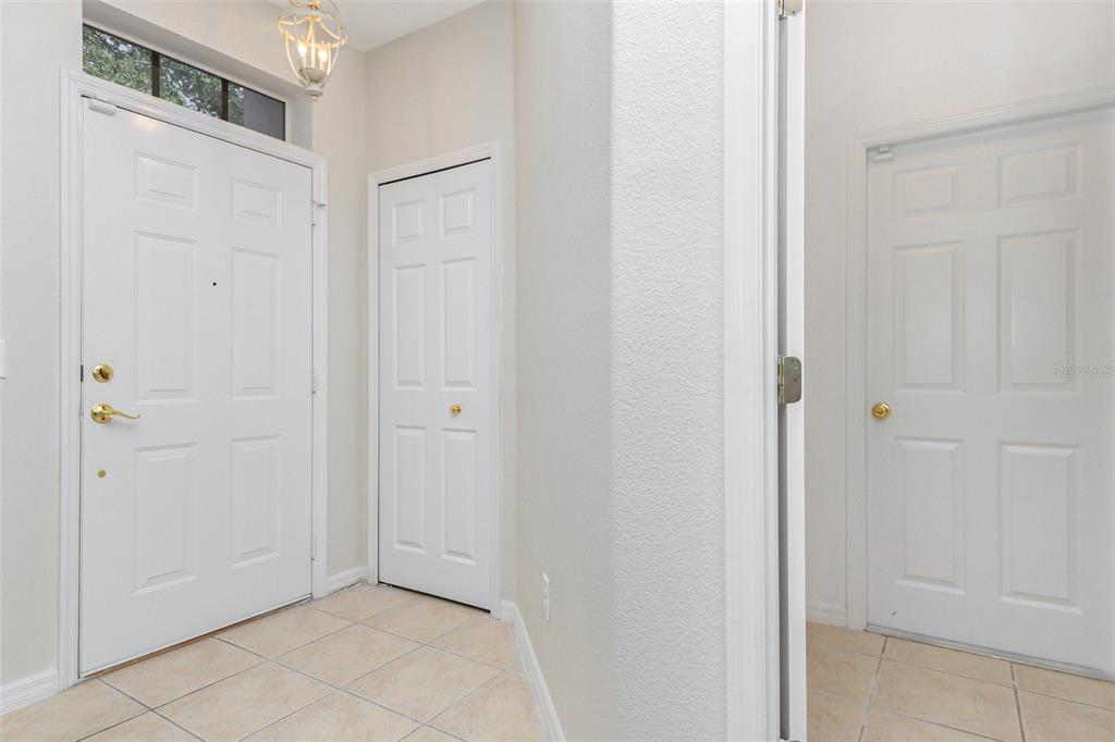 An entryway features a white front door, a closet door, and tiled flooring — 213 KNOLLWOOD DRIVE, DAVENPORT, FL