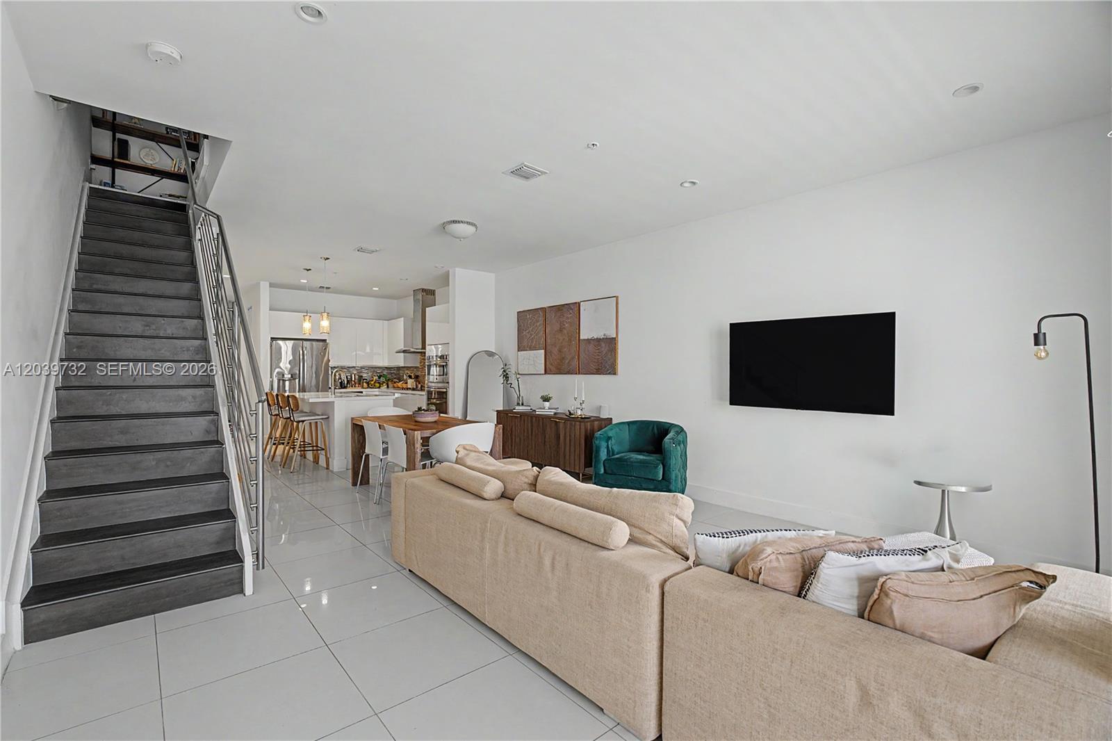 An open-concept living room features a staircase, kitchen, dining area, and a large sofa — 10260 NW 63 Terrace # 213, Miami FL 33178, MIAMI, FL
