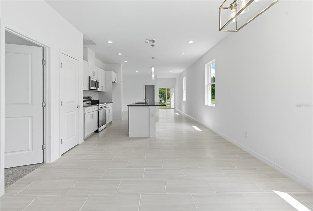 A bright, modern kitchen and dining area with white cabinets, a central island, and tile flooring — 817 S LOCUST AVENUE, SANFORD, FL